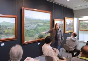 自身の作品を前に、かやぶき民家の魅力などを語る早津剛さん＝津南町下船渡