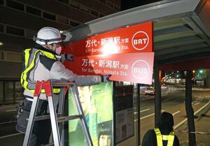 「BRT」から「BUS」に表示が取り換えられる礎町バス停=3月21日午後11時30分ごろ、新潟市中央区