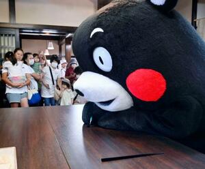 輪島塗の体験施設で箸を制作する「くまモン」=9日午前、石川県輪島市