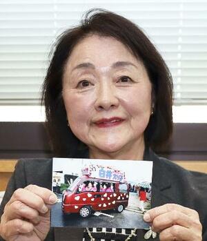 赤い車にハートのステッカーを貼った選挙カーの写真を手にする愛知県日進市議の白井依理子さん＝３月、日進市