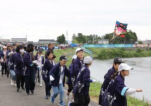 声を掛け合いながら堤防上を走り、凧を揚げる子どもたち＝３日、新潟市南区