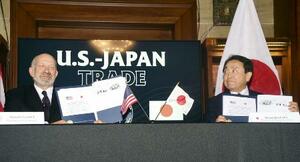4日、ワシントンで日米関税合意に関する文書に署名した赤沢経済再生相(右)とラトニック米商務長官。トランプ米大統領は日本から輸入する自動車への関税を引き下げる大統領令に署名した