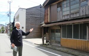 重伝建となる小木町の町並みを背に、魅力を語る岡崎拓夫さん=佐渡市小木町