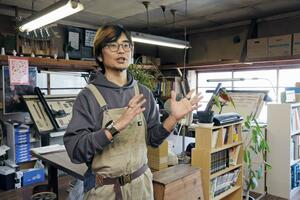 縫製工場の名残を感じる事務所で語る川﨑雄介さん。設計は2階で行っている=新潟市中央区