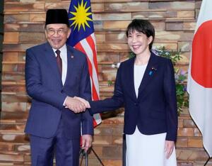 会談前に握手するマレーシアのアンワル首相(左)と高市首相=10日午前、首相官邸