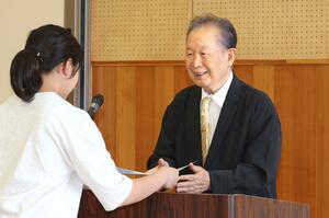 山古志小の児童に賞状を手渡す田中トシオさん=11日、長岡市山古志竹沢