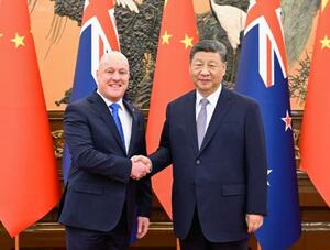 握手するニュージーランドのラクソン首相(左)と中国の習近平国家主席=20日、北京の人民大会堂(新華社=共同)