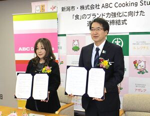 協定締結式で記念撮影に応じる志村なるみ社長(左)と中原八一市長=新潟市役所
