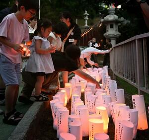 戦死した特攻隊員を悼む集いで、灯籠に明かりをともす子どもたち=21日午後、鹿児島県鹿屋市