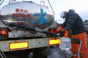 断水が起きている鳥取県南部町で、給水車から水をくむ町職員=7日午前7時21分