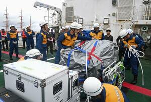 巡視船の甲板に積み込んだ通信機材をベルトで固定する海上保安庁の隊員ら=8日午後、富山県射水市