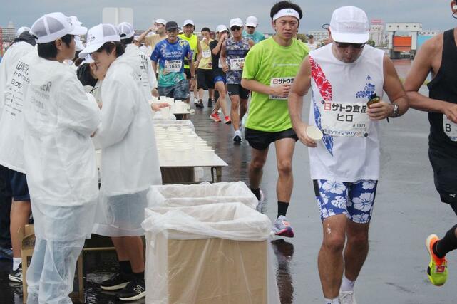 あらかじめ飲料が入った紙コップが並ぶ通常の給水所。ボランティアは対応に追われ、そばにはごみ箱が置かれている＝12日、新潟市西区
