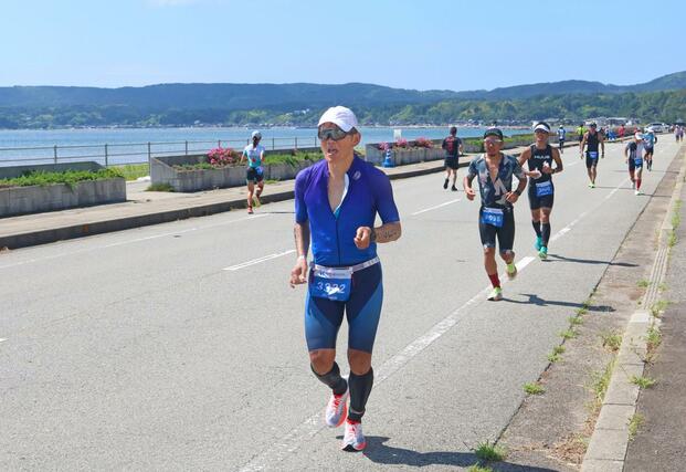 沿道の応援を受けながら海岸沿いを走り抜ける選手たち＝９月１日、佐渡市