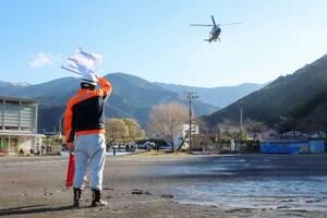 　集落孤立を想定した訓練で、警察のヘリに着陸を合図する町職員＝７日、静岡県西伊豆町
