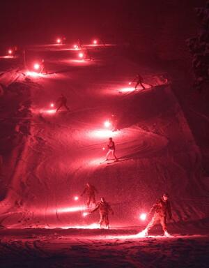 たいまつの炎で赤く照らされたゲレンデ＝上越市大貫