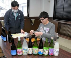 自身の写真作品をデザインしたラベルを酒瓶に貼る押山優樹さん(右)=上越市三和区塔ノ輪