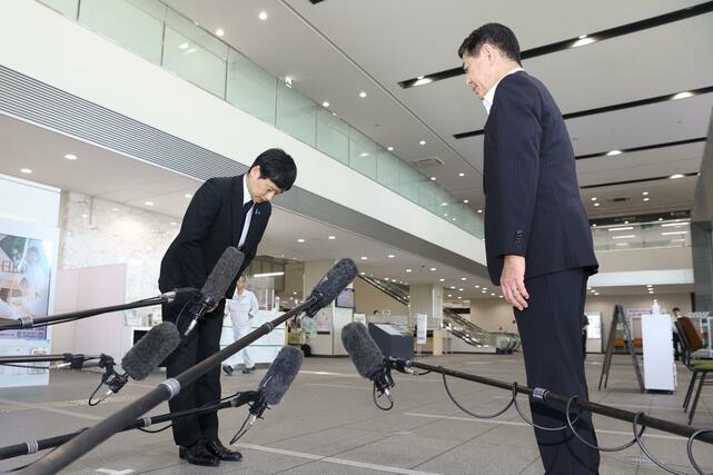 三田市の田村克也市長（右）に頭を上げる上越市の中川幹太市長＝２９日、兵庫県三田市の三田市役所