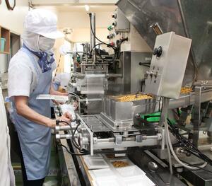 機械を使い、大豆を容器に入れる作業=新潟市秋葉区新町1