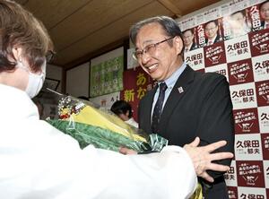 花束を受け取り、支援者と喜ぶ久保田郁夫さん=20日午後11時30分前、糸魚川市寺島1