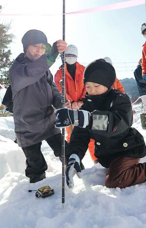 ビーコンやゾンデ棒を使い、雪に埋まったぬいぐるみを捜索する親子=上越市板倉区猿供養寺