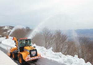 弧を描くように雪を飛ばしながら進む除雪車=4月3日、佐渡市の大佐渡スカイライン