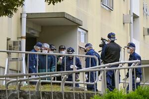 集合住宅の入り口付近で現場検証をする大阪府警の捜査員=9日午前11時51分、大阪府和泉市