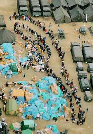 阪神大震災の避難所となった小学校の校庭で、救援物資の配給に並ぶ被災者の長い列=1995年1月、神戸市東灘区