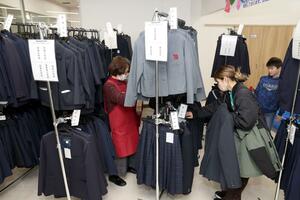 リユース制服の販売会でブレザーを買い求める親子=14日、長岡市台町2