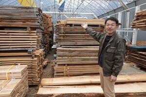 　登米町森林組合が保有する木材の簡易乾燥室に立つ会津浩幸さん＝宮城県登米市