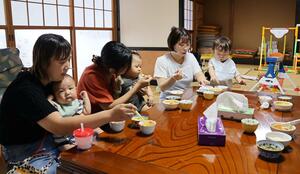 テーブルを囲み、子どもに離乳食を食べさせながら交流する参加者ら=三条市西中