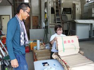 コメの出荷に向けた作業を手伝うアルテゴの社員(右)=柏崎市高柳町門出
