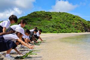 　学童疎開船「対馬丸」の犠牲者が漂着した海岸に花を手向ける児童ら＝２４日午前、鹿児島県・奄美大島の宇検村