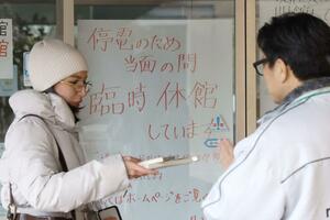 停電で臨時休館している県立図書館。来館した女性から職員が本を受け取る＝４日、新潟市中央区