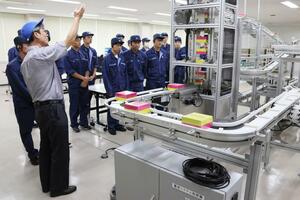 小川コンベヤで搬送システムなどを見学する長岡工業高専の学生たち=長岡市滝谷町