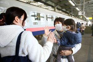 つかの間の帰省を終え、別れを惜しむ家族連れ。互いに姿が見えなくなるまで手を振る=3日、長岡市のJR長岡駅