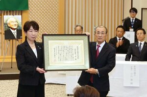 故・佐野藤三郎さんに代わって表彰状を受け取る長男の正人さん(右)=10月25日、新潟市中央区一番堀通町