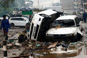 　７日、ケニア・ナイロビで、豪雨の影響で大破した車両の近くを歩く女性（ロイター＝共同）