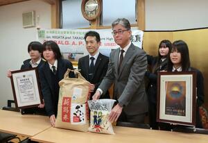 富寿しの宮嵜富夫副社長(右から3番目)らに米を手渡す高田農業高の生徒=上越市南本町3