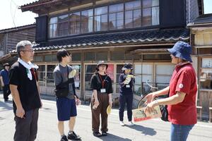 ガイドと一緒に伝統的な町並みを見て歩く参加者=佐渡市小木町