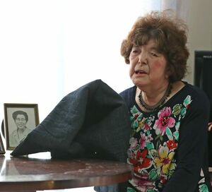語り部の活動で使う防空頭巾を手に、母の写真の前で思い出を語る古田セツ子さん=新発田市豊町1