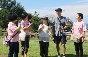 地元の女性たちから案内を受ける移住体験中の髙江洲さん夫妻(中央2人)=村上市瀬波温泉3