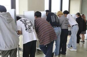 　２０２４年６月、高校で実施された東京都知事選の模擬投票で、候補者の名前を記入する生徒たち＝東京都練馬区