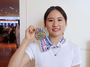 米国遠征から帰国し、金メダルを手にする女子高飛び込み世界選手権代表の金戸凜=17日、羽田空港