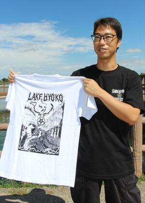 瓢湖の水鳥メタルTシャツを手に持つ土井一心太さん=阿賀野市水原