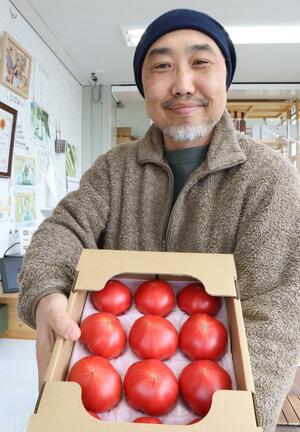 全国トマト選手権で金賞になった「越冬トマト」を手にする曽我新一さん=新潟市北区木崎
