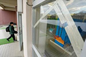 　学校が再開し、登校する青森県八戸市立江南小の児童。手前は地震でひび割れたガラス＝１０日午前７時３７分