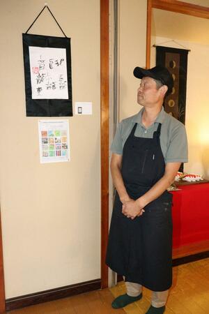 割烹大倉屋の店内に飾ったアートレンタルの書道作品を紹介する大倉雄二さん=新潟市北区嘉山1