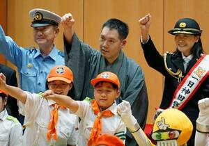 警視庁神田署の交通安全啓発イベントで腕を振り上げる、講談師の神田伯山さん(後列中央)と高橋建次署長(同左)ら=7日午後、東京都千代田区