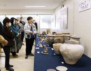 遺跡出土品展で市職員による解説を聞く来場者ら=燕市水道町1