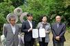 慰霊碑の前で合意書に調印した日弁連の渕上玲子会長(左から3人目)ら=6日、上越市名立区